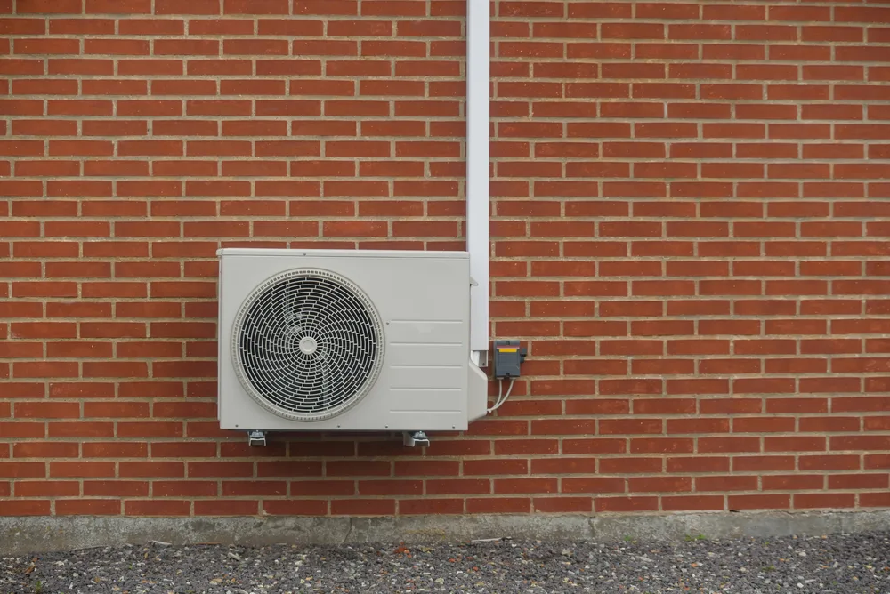 Outdoor air conditioning unit mounted on a brick wall.
